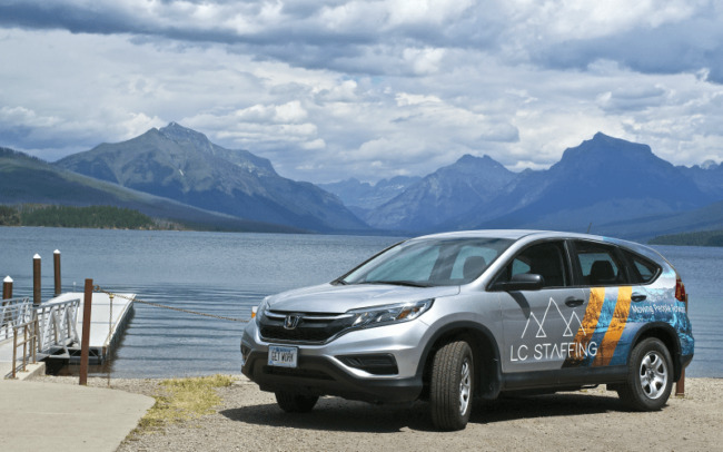 LC Staffing Logo car on the shore of a lake with mountains in the background