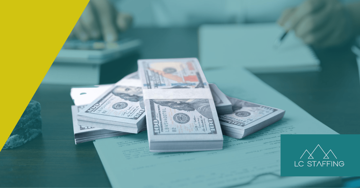 Stacks of cash on a desk representing Montana vs Idaho salary benchmarks for regional employers.
