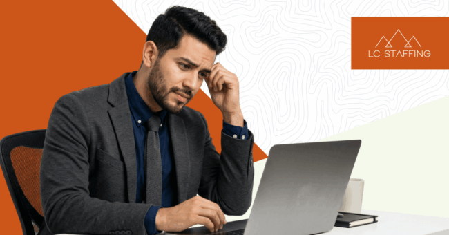 A man in a suit sits at a laptop looking frustrated, reflecting the skilled trades retirement gap Montana employers face in construction and manufacturing.