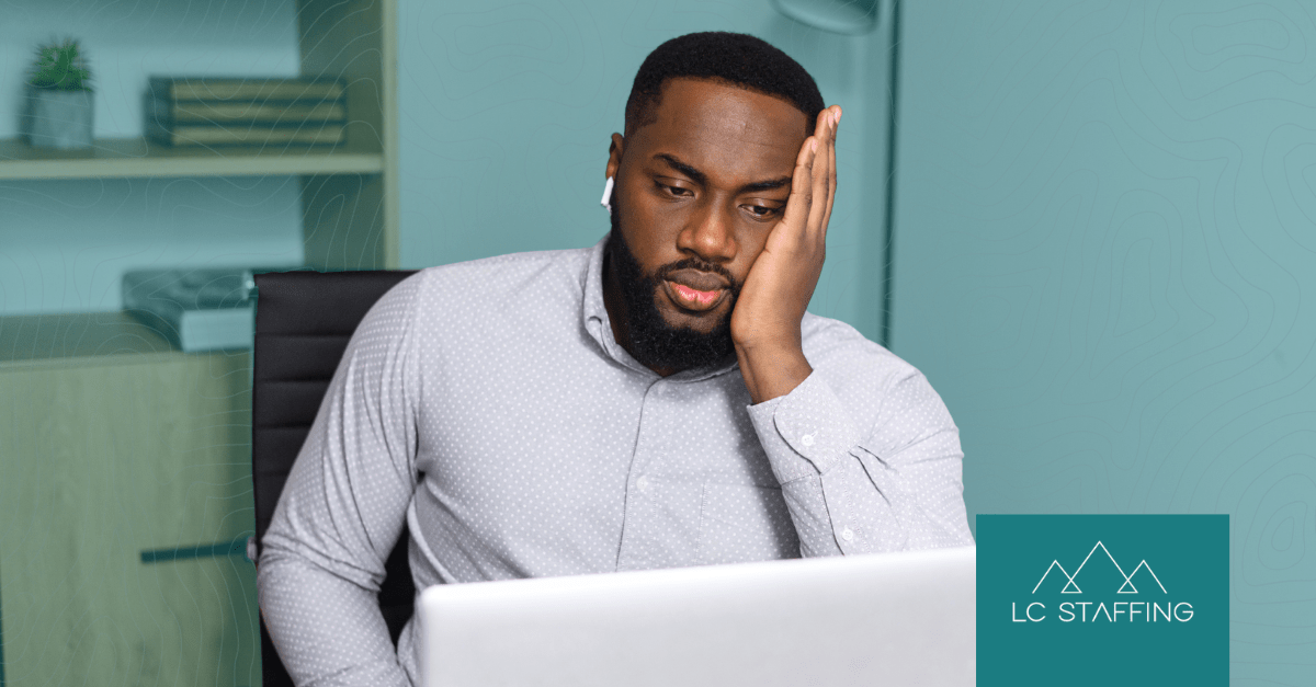 A frustrated hiring manager at his laptop dealing with hiring bottlenecks that slow down the recruitment process.